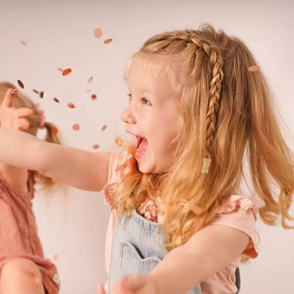 Kids Zwei Mädchen lachen während sie Konfetti werfen.