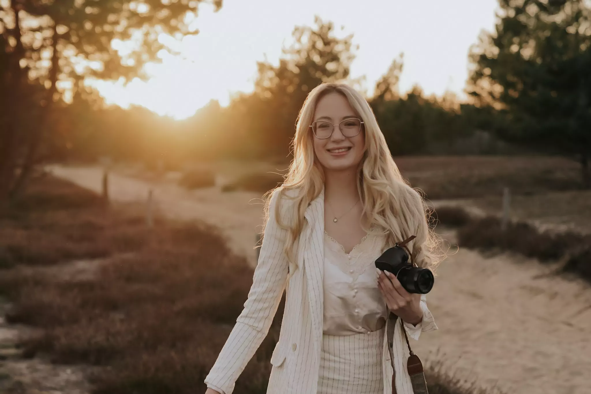 Alica lacht herzlich und hält eine Kamera in der Hand.